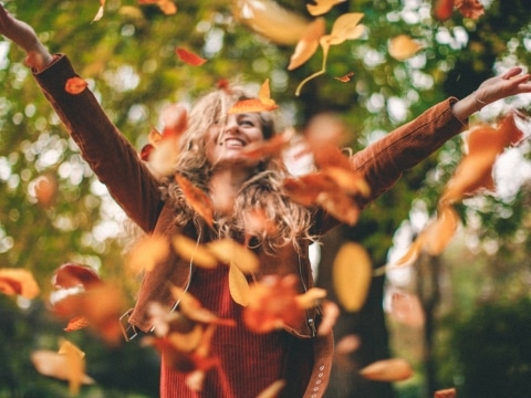 Frau wirft Herbstlaub in die Luft