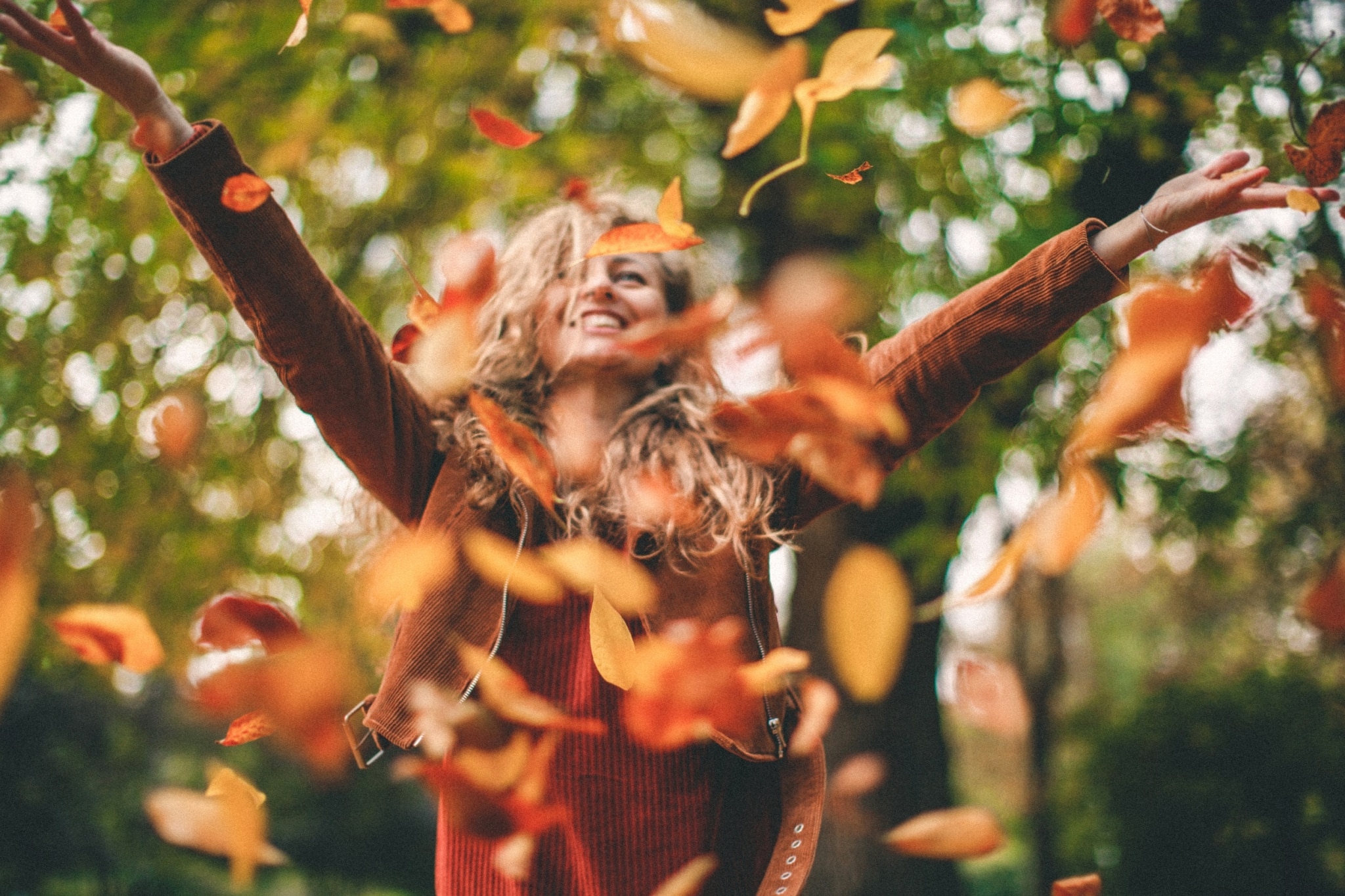 Frau wirft Herbstlaub in die Luft