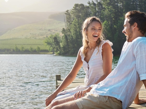 Junges Paar sitzt im Sommer auf einem Steg am See